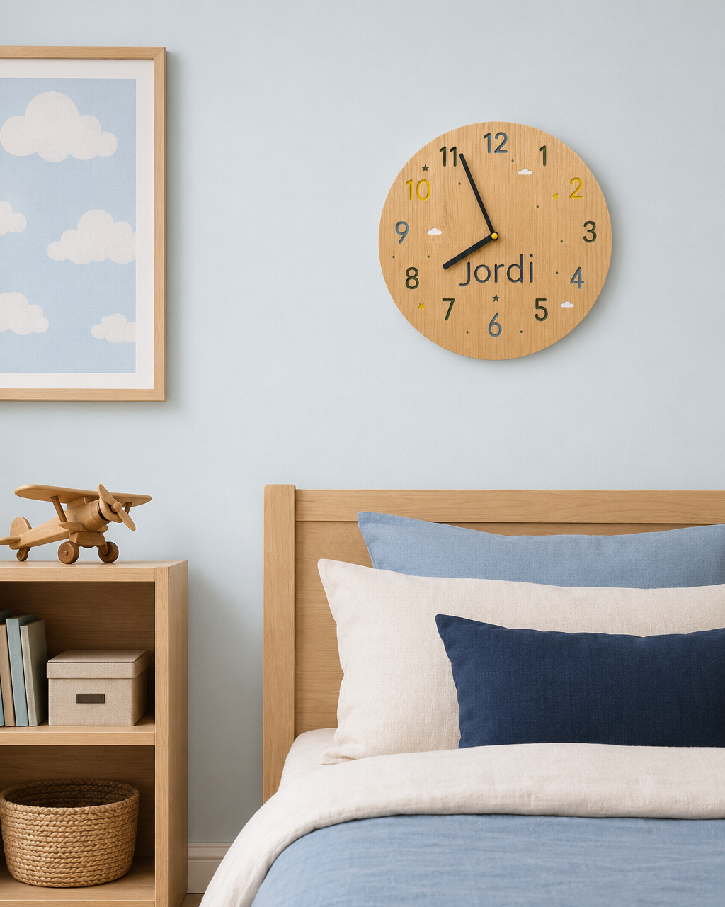 Reloj de madera personalizado con nombre sobre cama infantil con ropa de cama azul