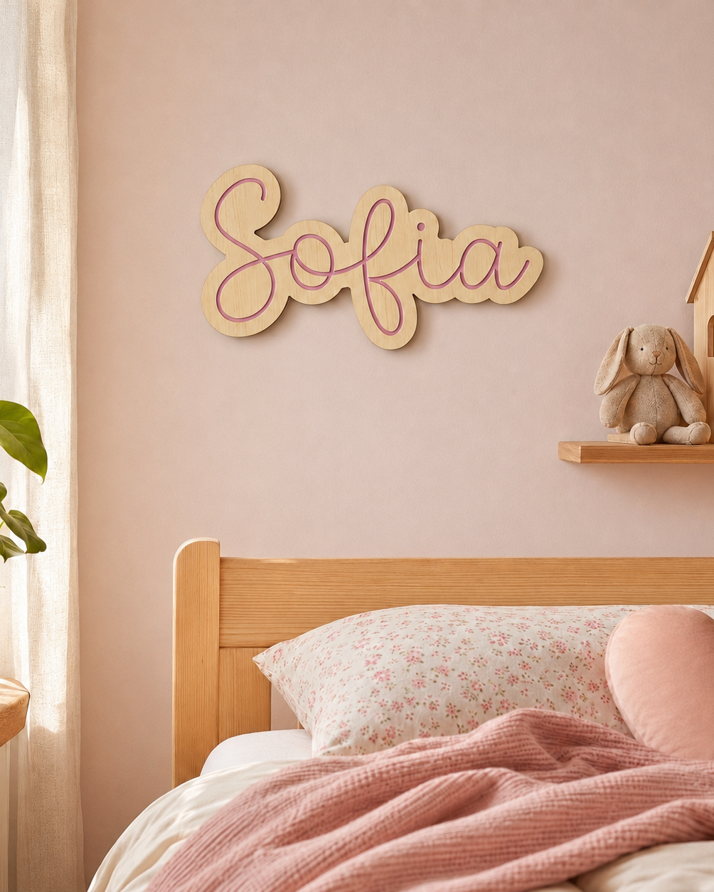 Nombre de madera Sofía en letra cursiva colgado en la pared sobre cama infantil rosa